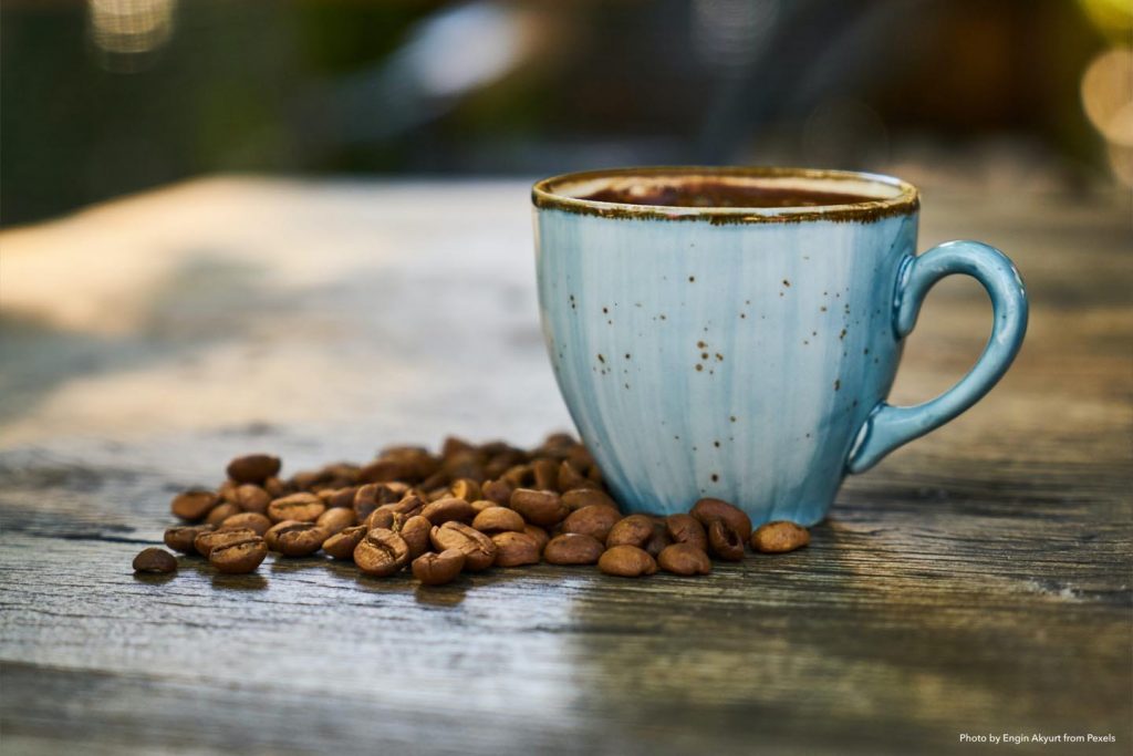 a blue coffee cup with coffee beans next to it