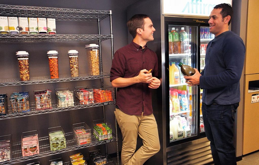 Coworkers interact at their workplace pantry while enjoying snacks and beverages - office pantry service